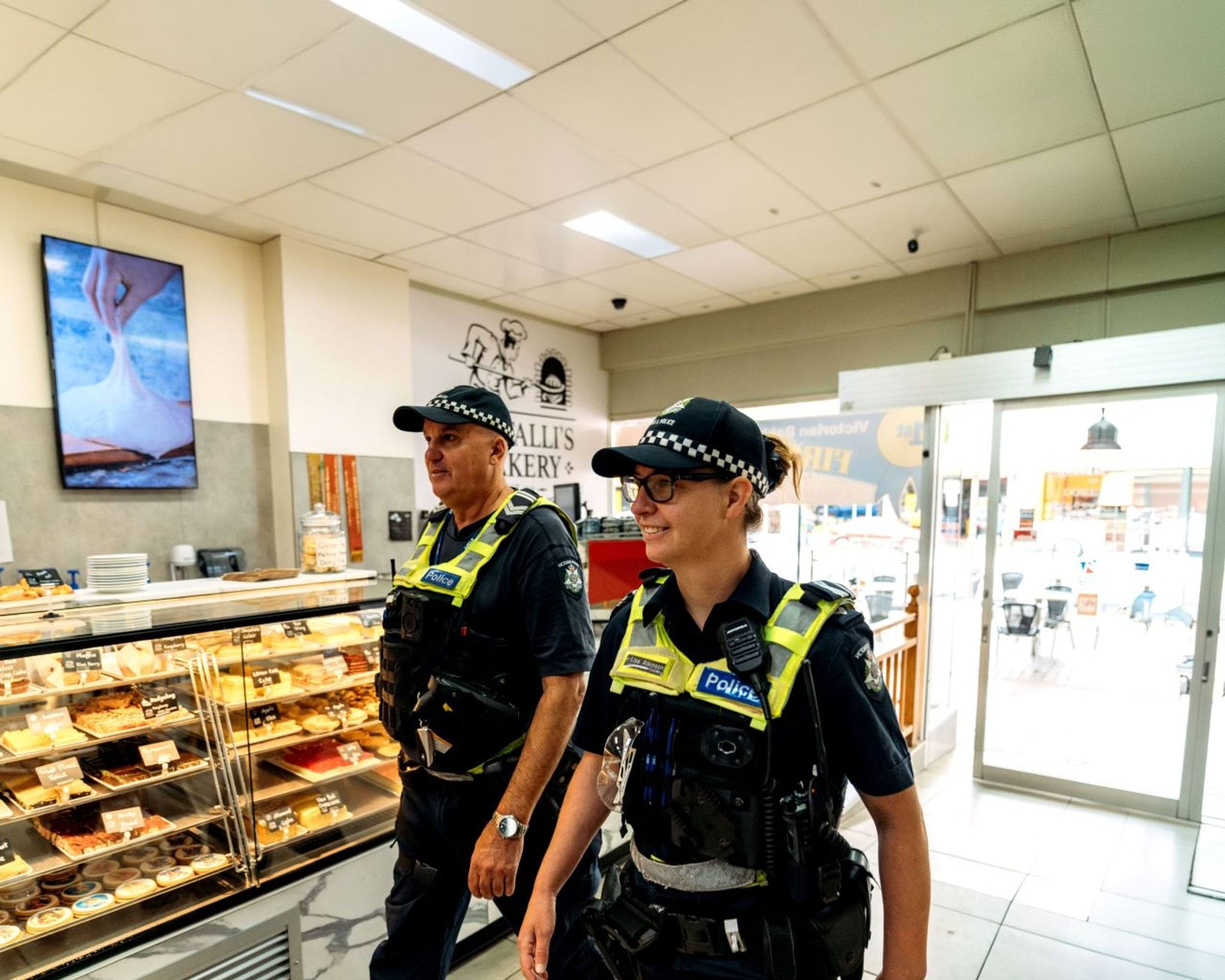 Two police officers walking into a bakery.