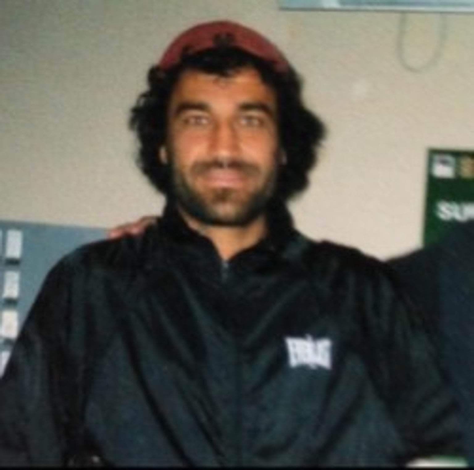 Jamal wearing a black jacket and a red cap. 