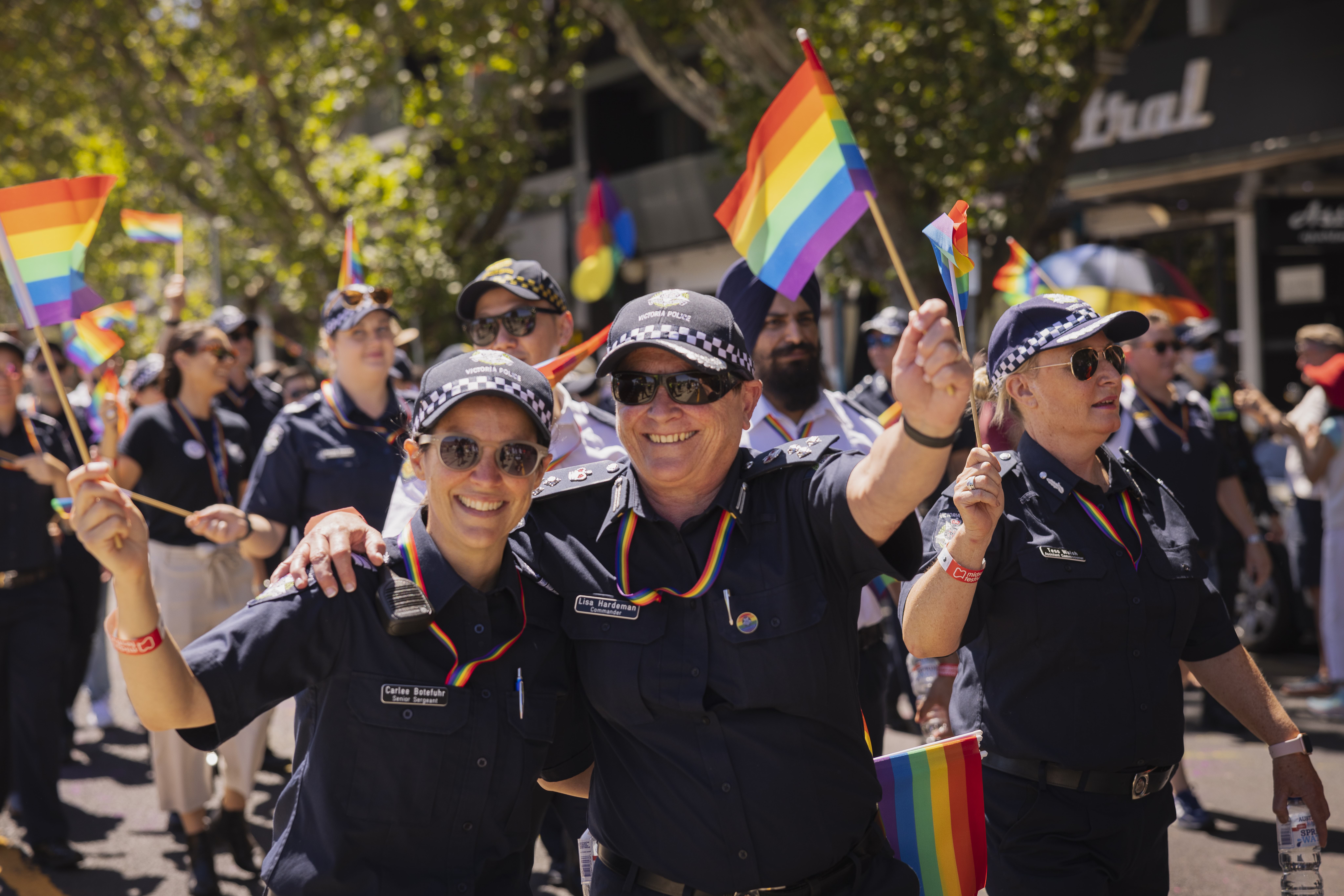Two LLOs in dark blue police uniform stand with rainbow flags.