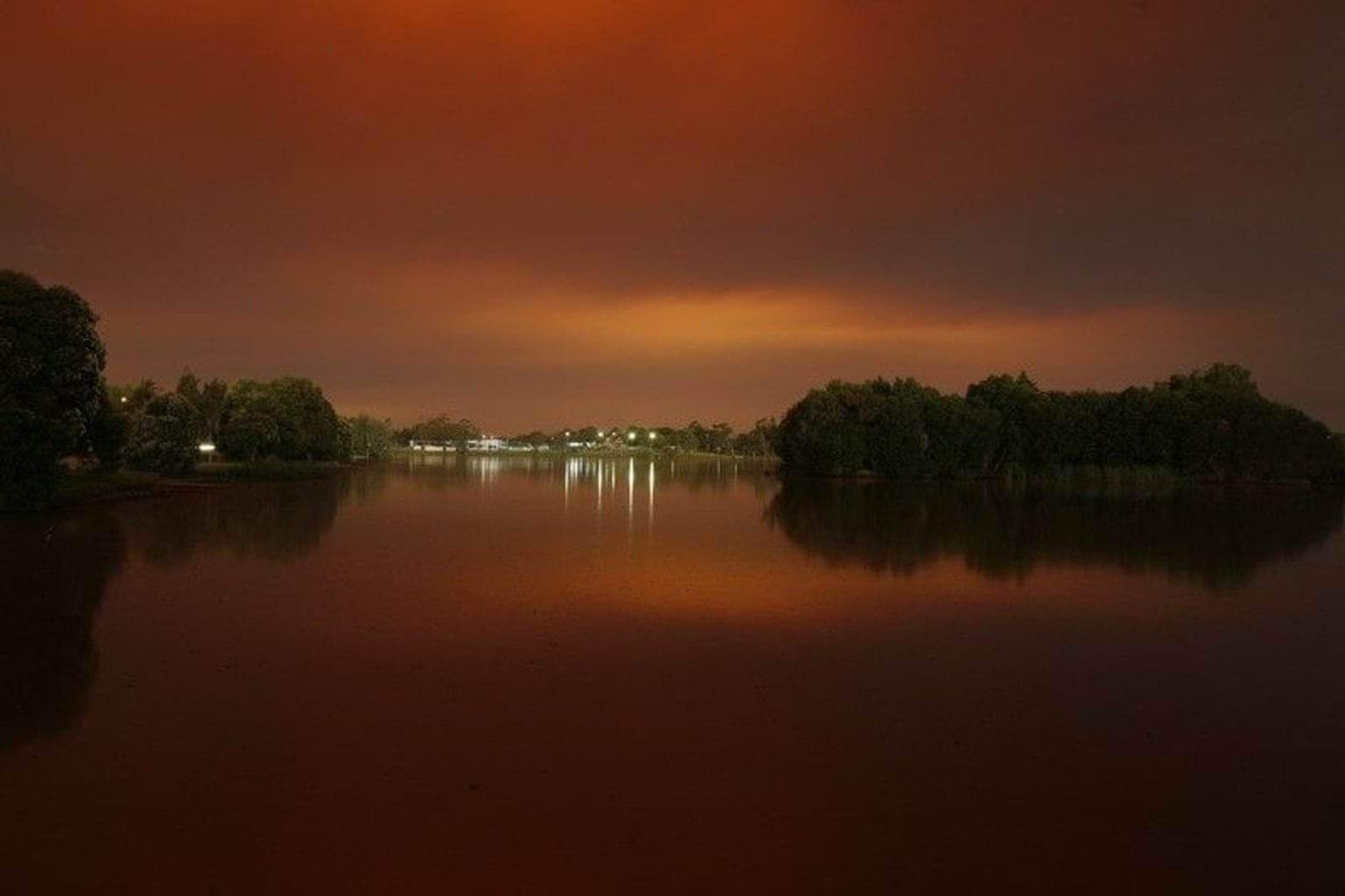 Victorian bushfires 2019-2020 - Distant marina lights with black and orange sky reflecting on water surface