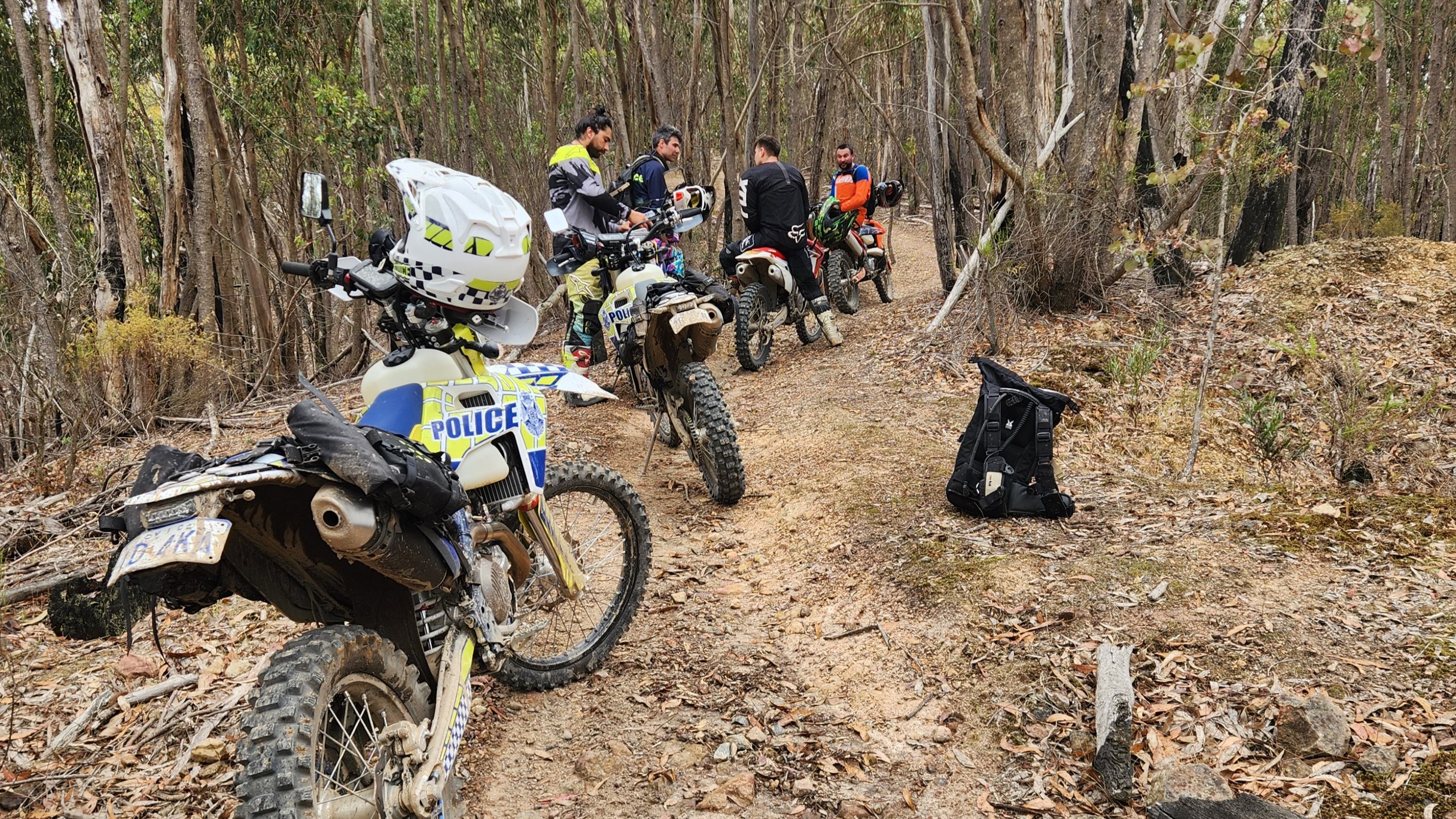 Police officers on motorbikes speak to motorcycle riders on a dirt road