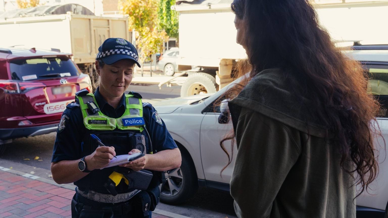A police officer speaking to a member of the public and taking notes.