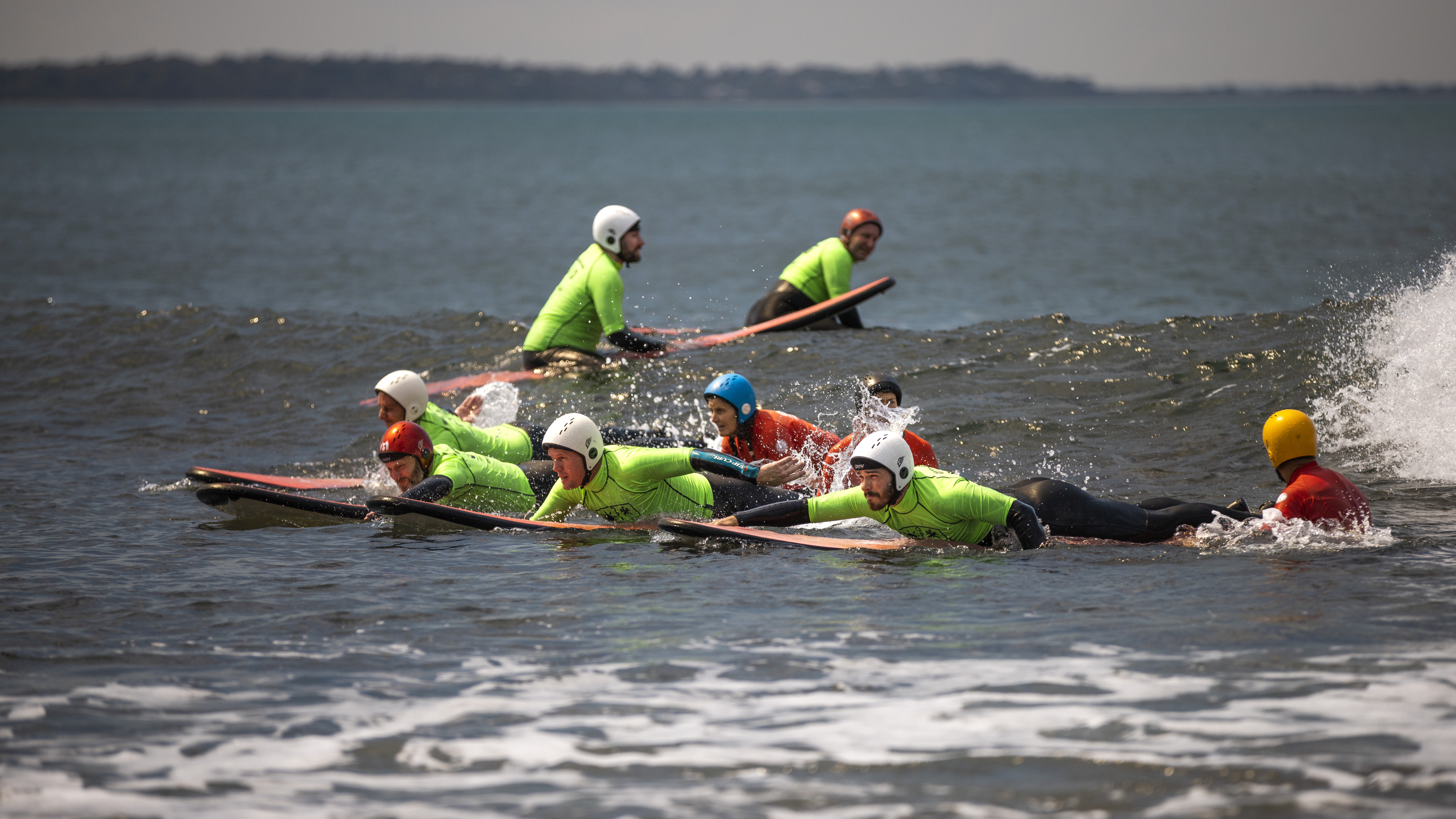 Police Life - Emergency services members wearing bright green wetsuits surfing in the ocean