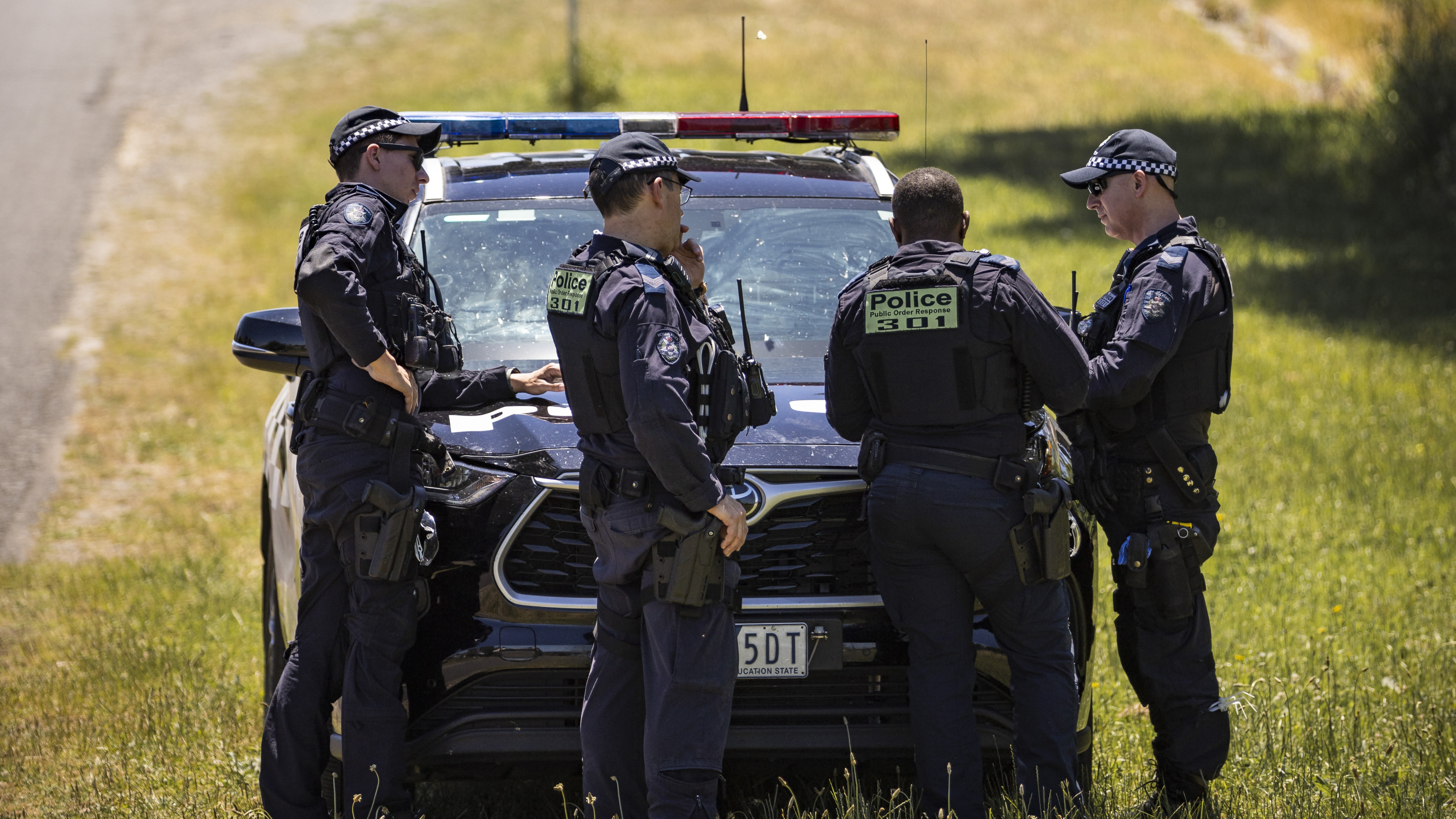 Police Life - A group of Public Order Response Team officers standing in front of a police car parked in dry grass