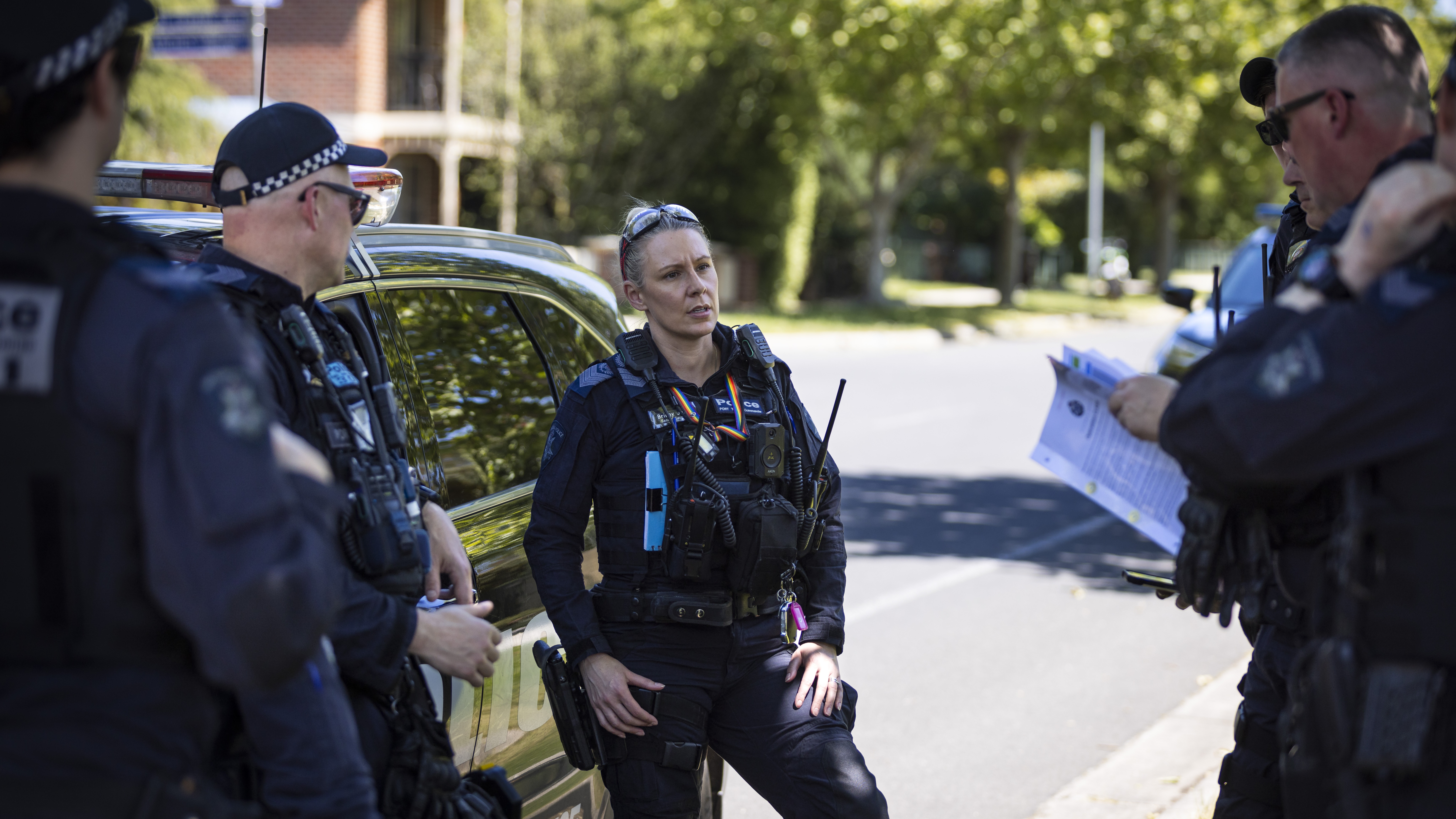 Police Life - Female Public Order Reponse Team officer speak to other officers in front of a police car
