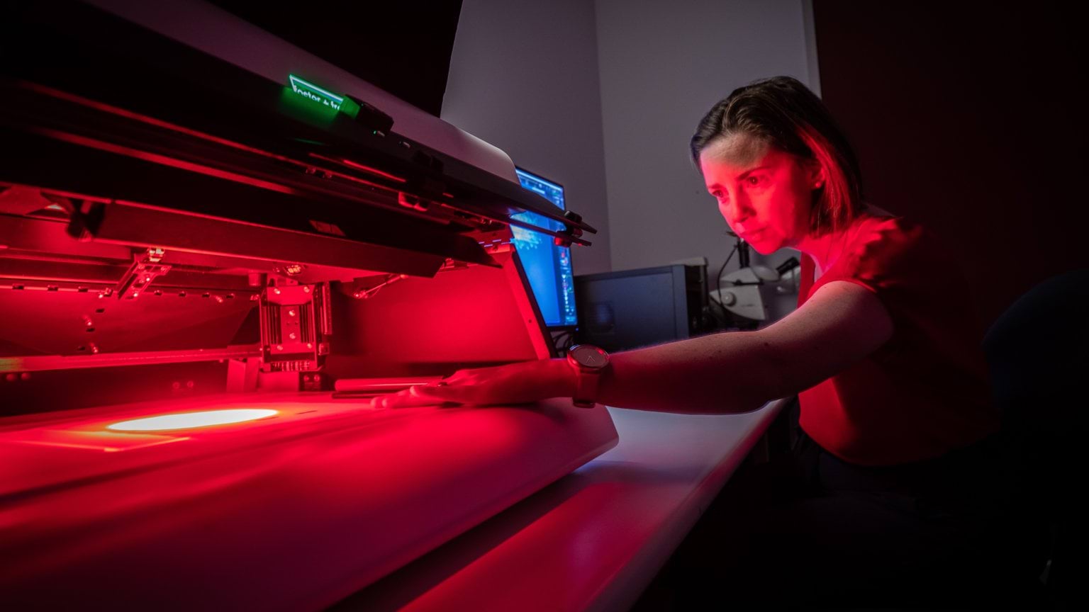 Police Life - Female forensic officer examining a document under red light