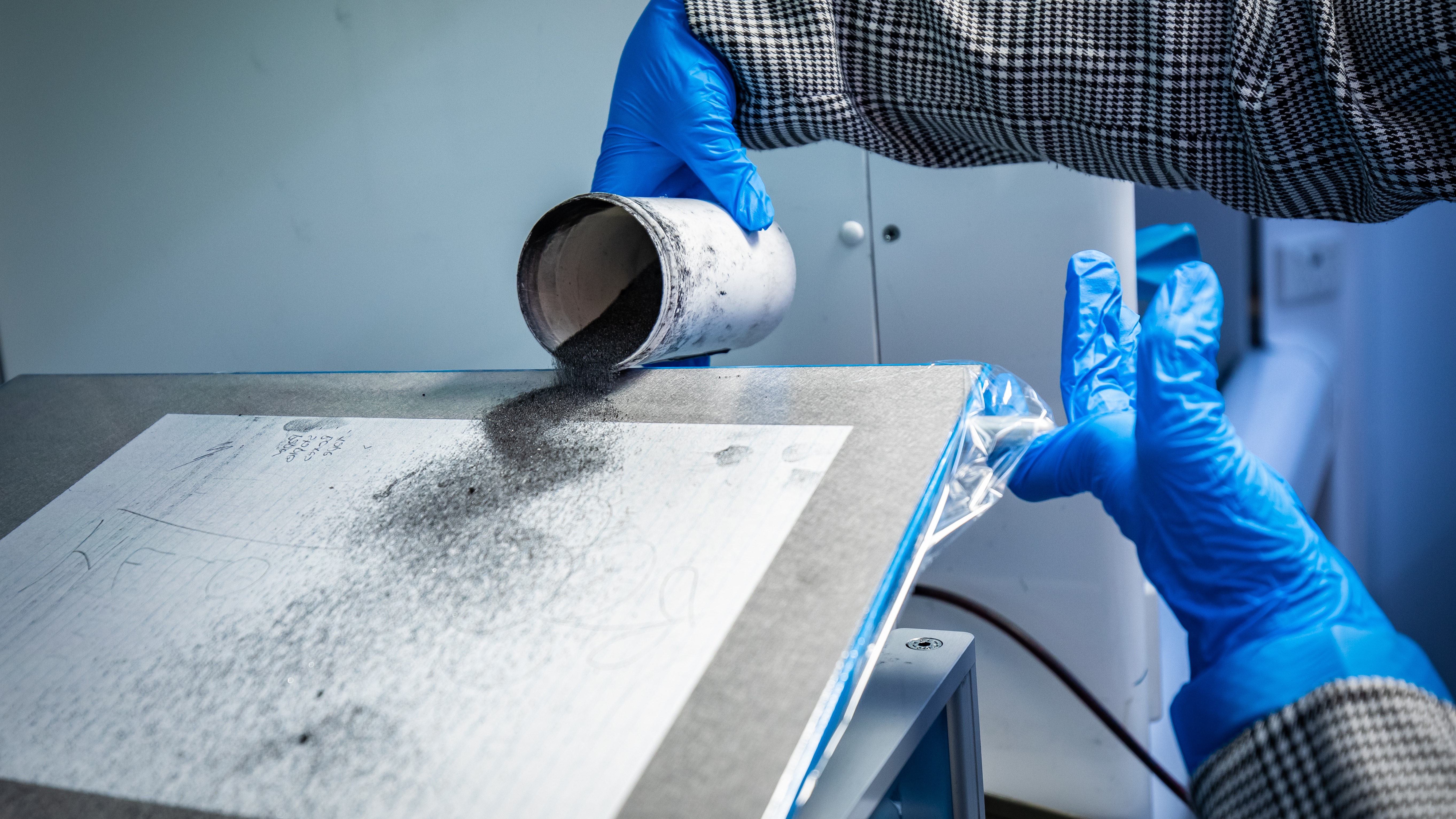 Police Life - Graphite dust being poured on a piece of paper sitting on a metal plate
