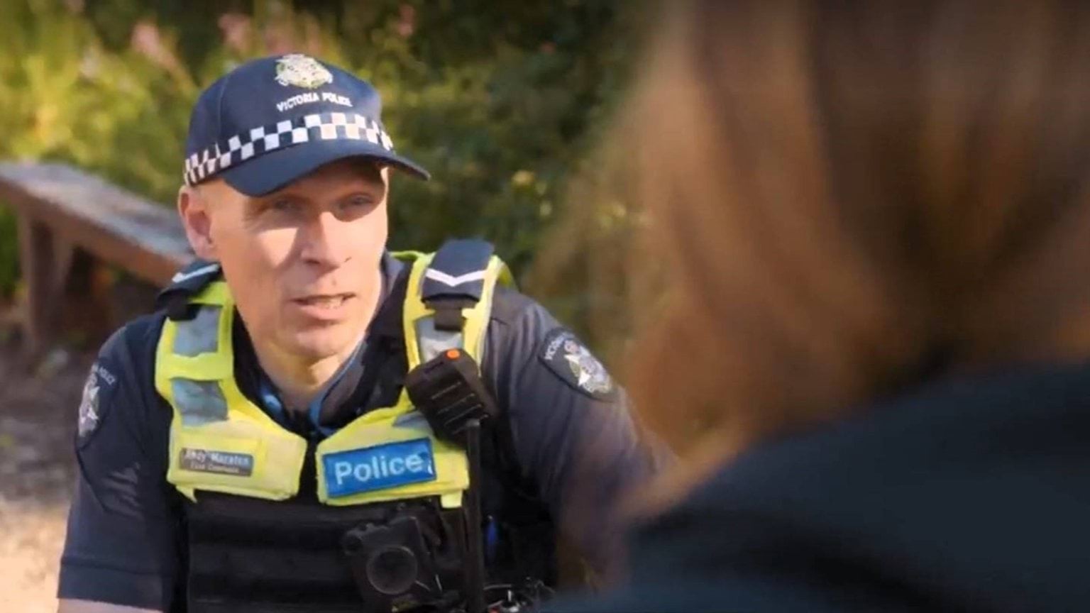 Police Life - image of male police officer talking to a person who's back is to the camera.