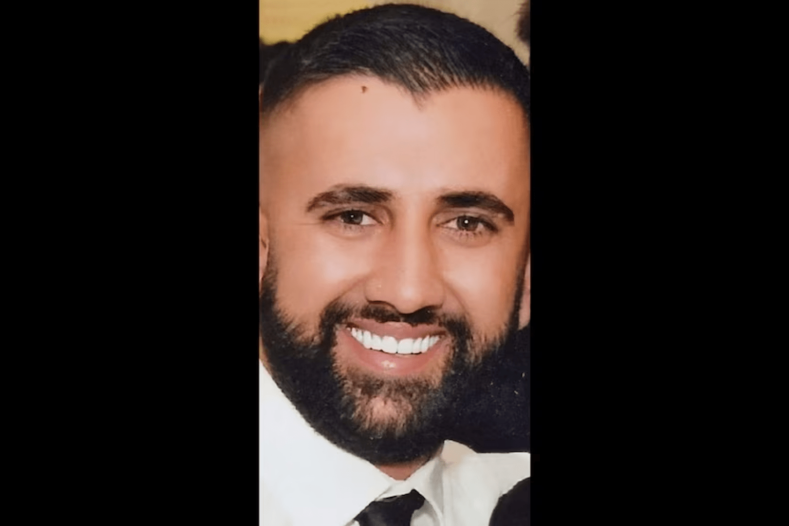 Robert Issa, with short black hair and a black beard, wearing a white shirt with black tie. 