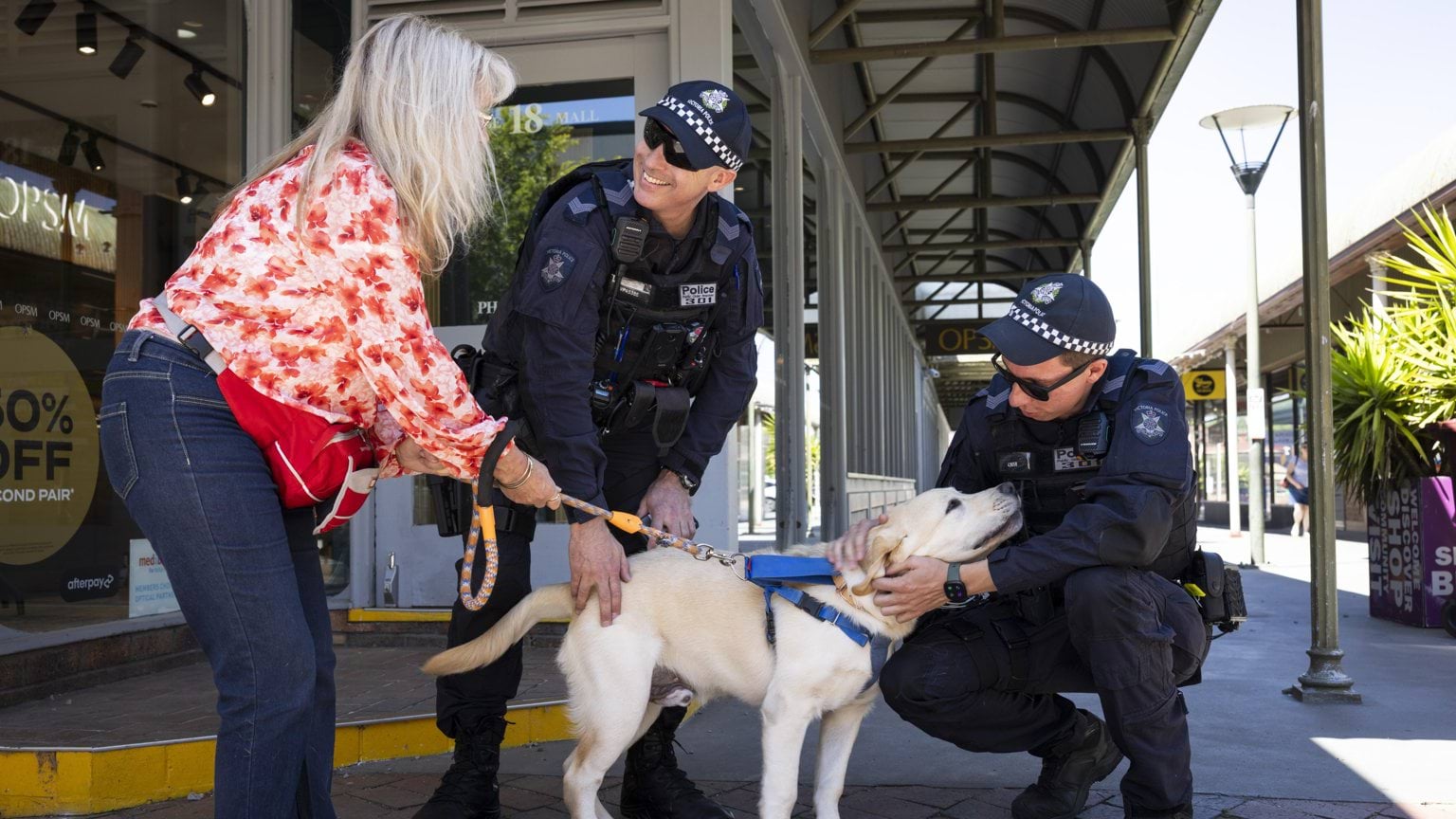 Two male Public Order Response Team officers interacting with a woman and her dog
