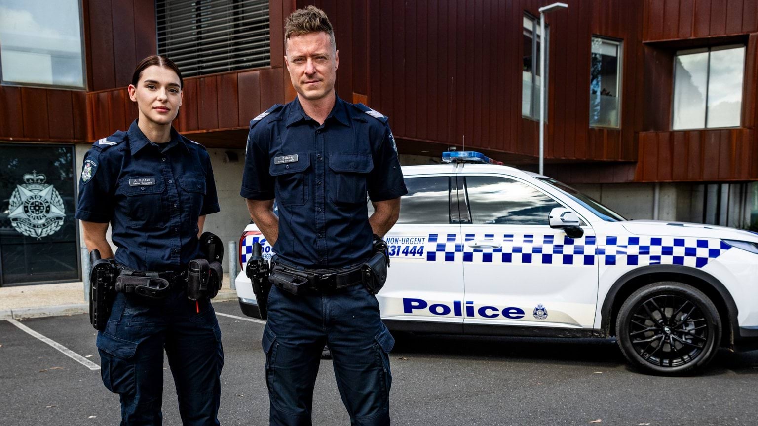 Police Life stories - Sen Const Amy Holden and Act Sgt Trent Delaney in uniform standing in front of police car