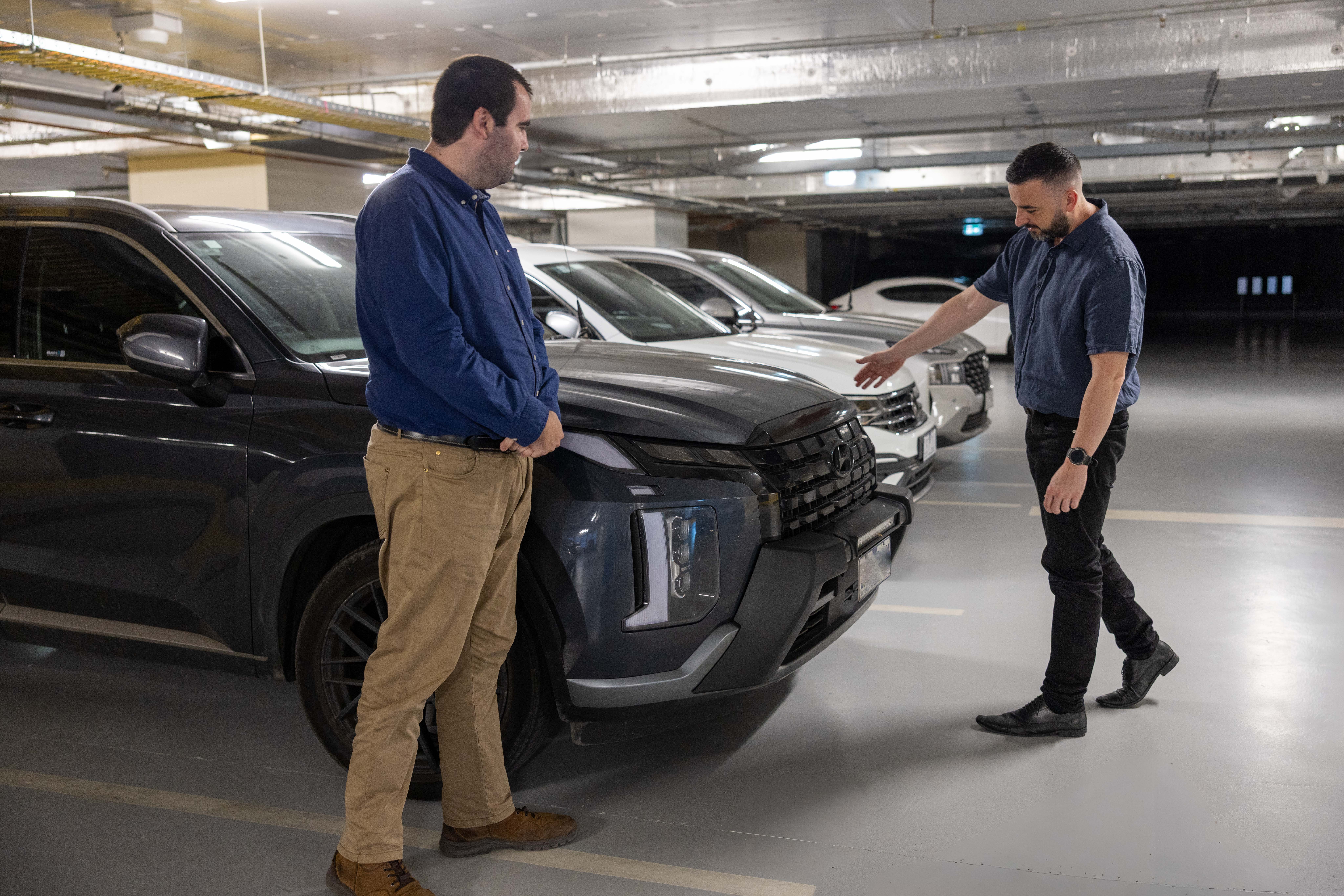 Police Life - two employees examine the features of a car in a carpark