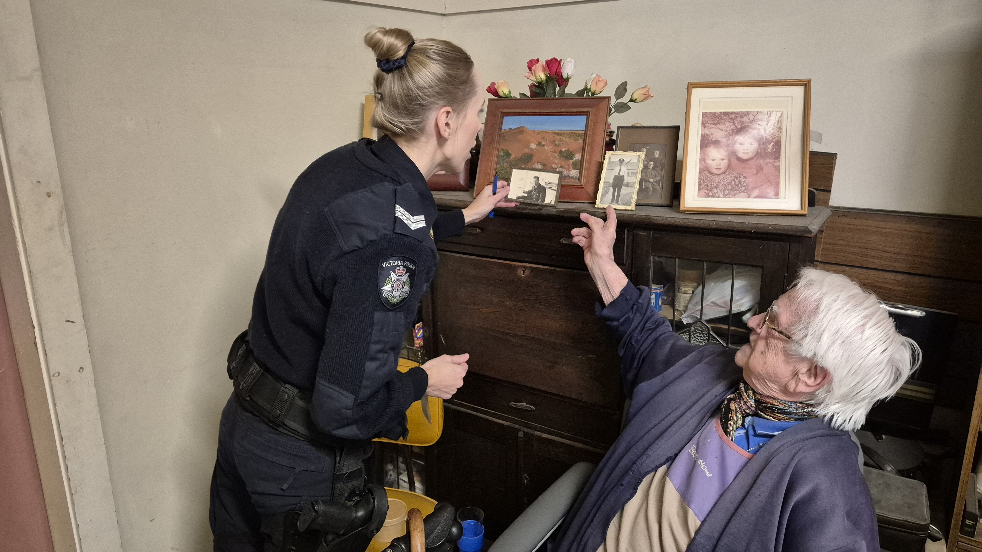 Elderly woman showing a police member a photograph of her husband