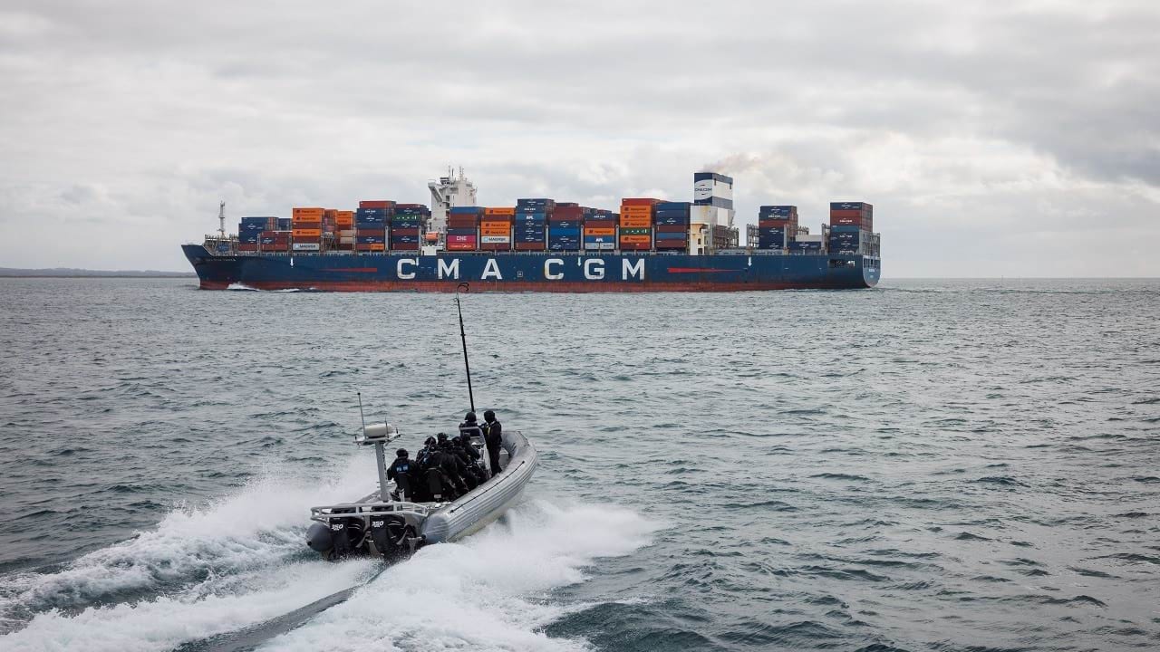 Water Police in a boat driving towards a container ship