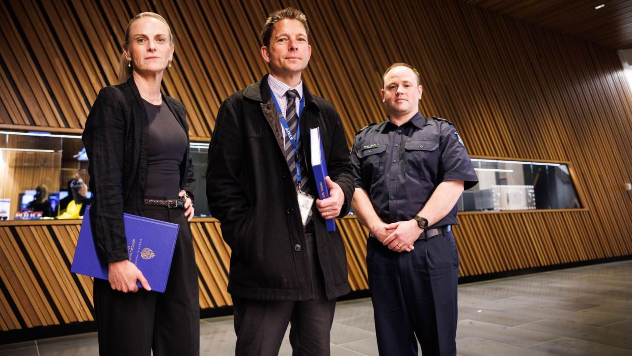 Three detectives standing in a corridor