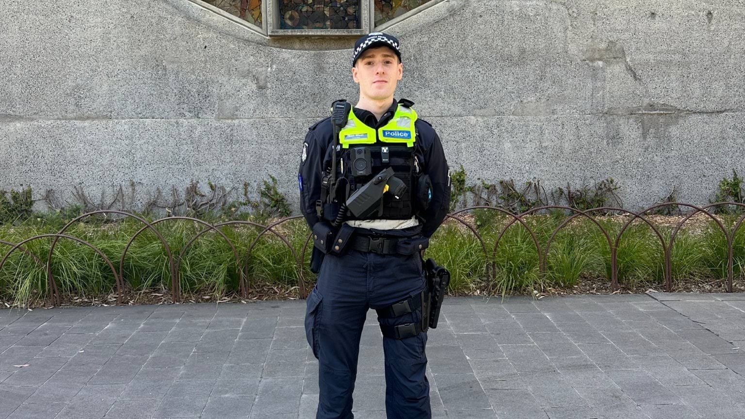 Male police officer standing in front of a concrete building