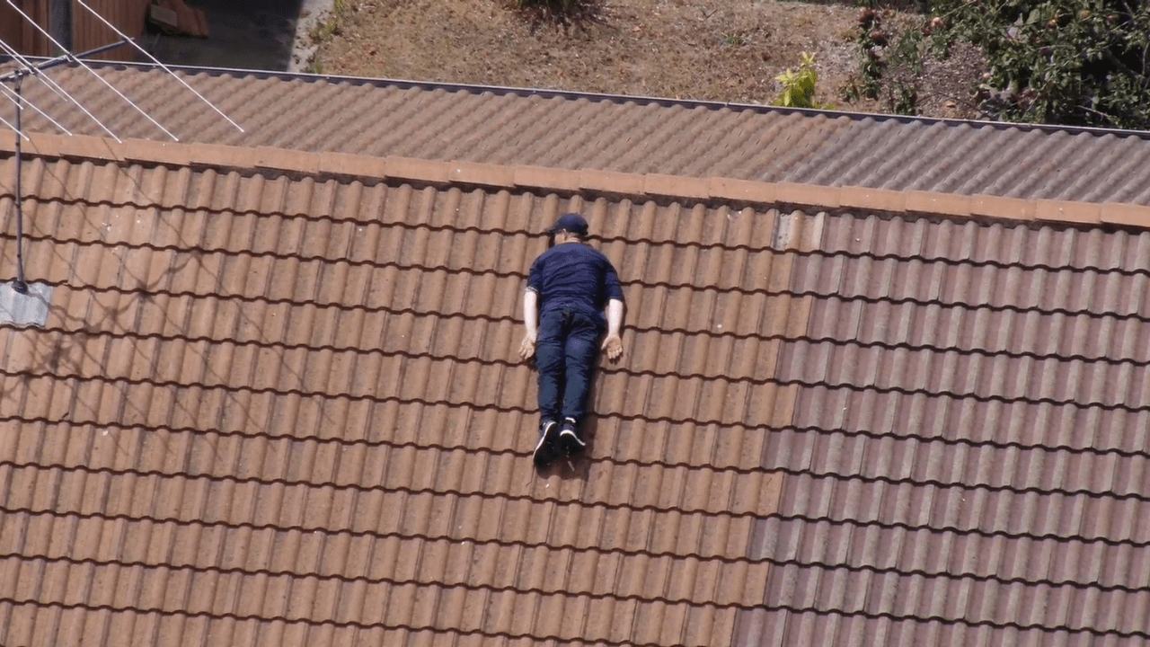 Police Life - A person of interest lies prone on a rooftop 