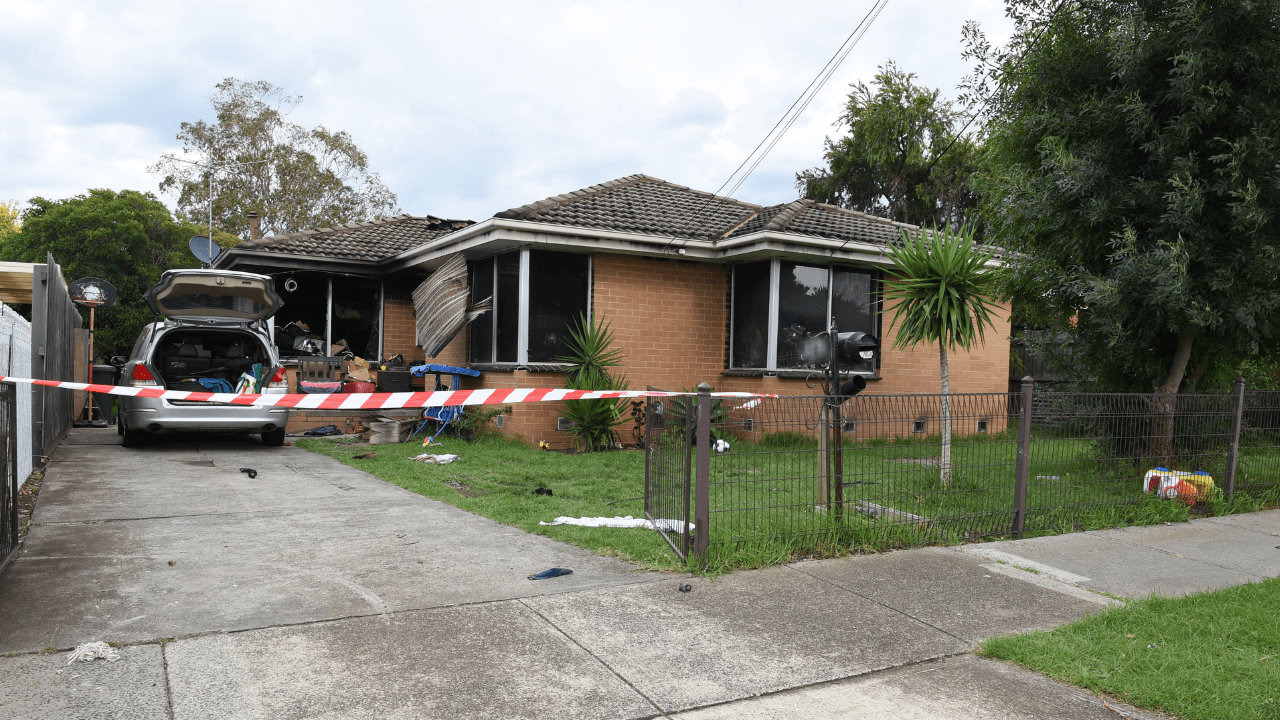 Police Life - Red-and-white striped warning tape is strung across the driveway of a brick home that has been damaged by fire.