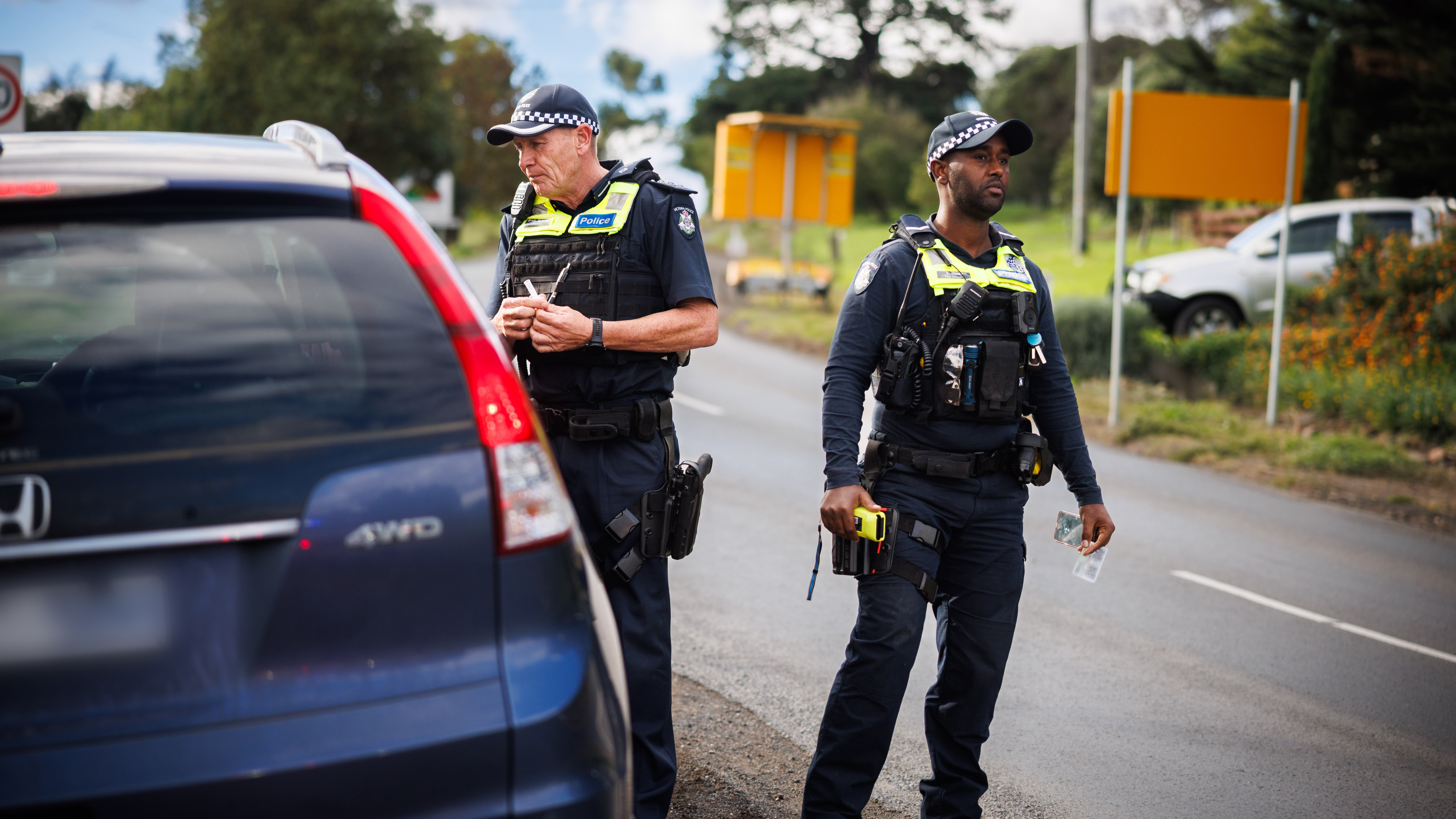 Two police members standing next to a vehicle