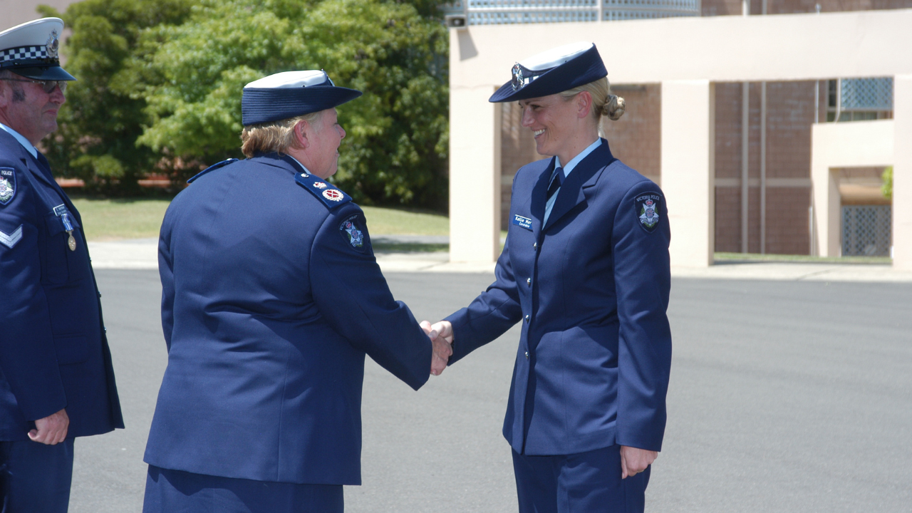 Det Ldg Sen Const Kellie Mervin is pictured at her graduation from the Victoria Police Academy, shaking hands with then-Chief Commissioner Christine Nixon.