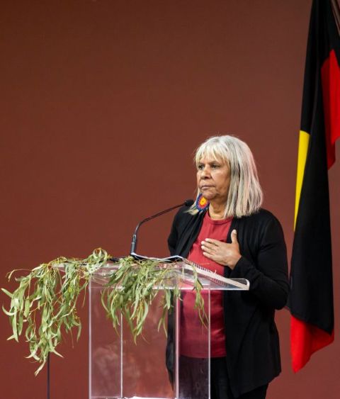 Aunty Eva-Jo Edwards giving a talk while standing at a podium that is covered in eucalyptus leaves.